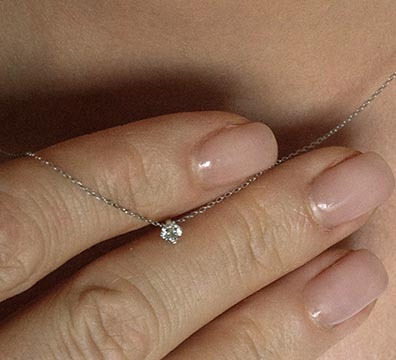 Diamantanh&auml;nger aus Wei&szlig;gold &ndash; Hand tr&auml;gt feinen Diamantanh&auml;nger