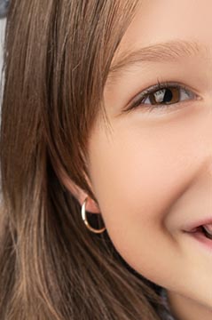 Creolen f&uuml;r Kinder &ndash; l&auml;chelndes M&auml;dchen mit kleinen goldenen Creolen