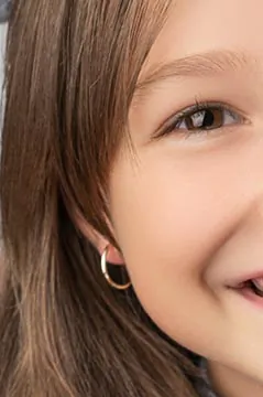 Creolen f&uuml;r Kinder &ndash; l&auml;chelndes M&auml;dchen mit kleinen goldenen Creolen