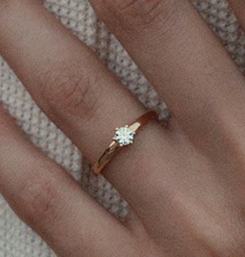 Verlobungsring mit Diamant &ndash; Nahaufnahme eines Solit&auml;rrings aus Wei&szlig;gold am Finger